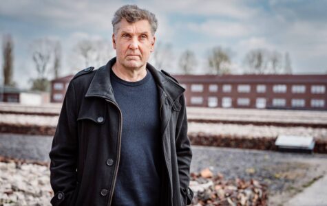 Ein Mann mit grauen Haaren und ernstem Blick steht auf dem Gelände der Gedenkstätte Neuengamme.